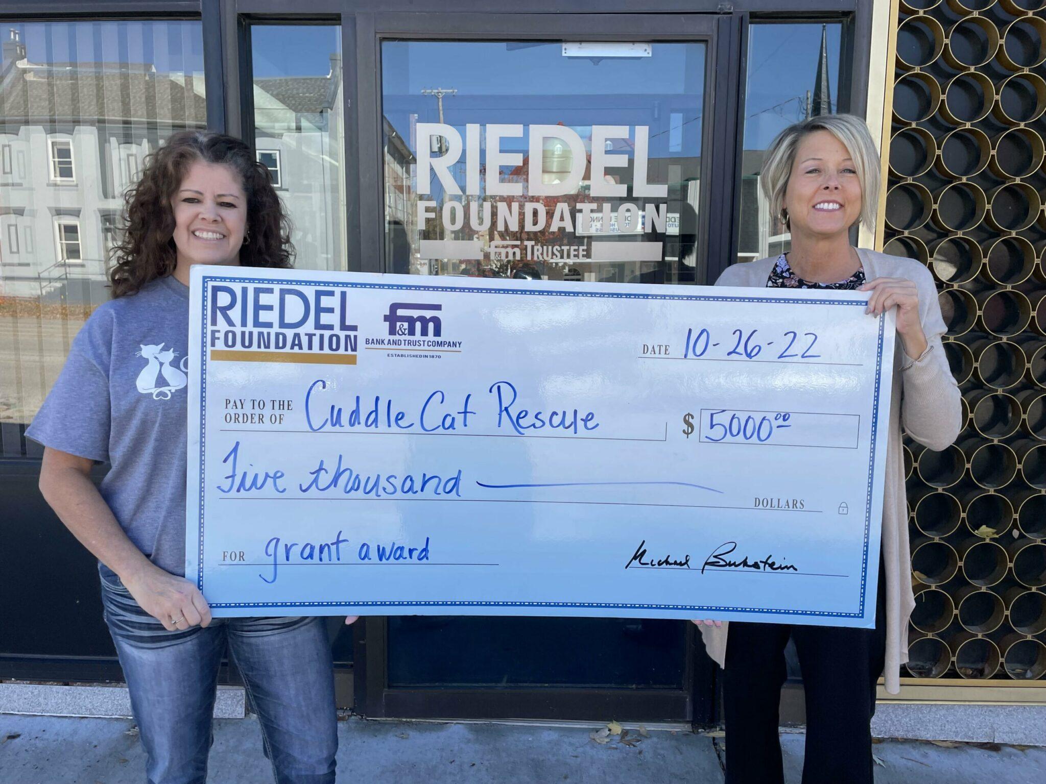 Riedel Trustee April Baldwin presents a check to Maria Poindexter with Cuddle Cat Rescue