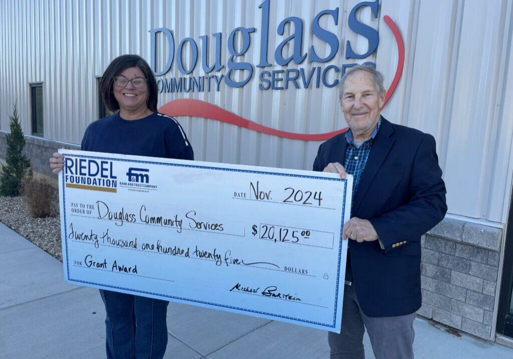 Douglass Community Services CEO Stephanie Cooper accepts a matching grant award from Riedel Foundation Lead Trustee Michael Bukstein.