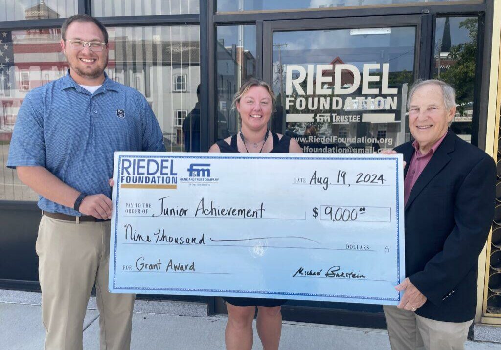 JA District Manager Taylor Rakers and JA Board Member Andrea Campbell accept a $9,000 grant award from Riedel Foundation Trustee Dr. Michael Bukstein.