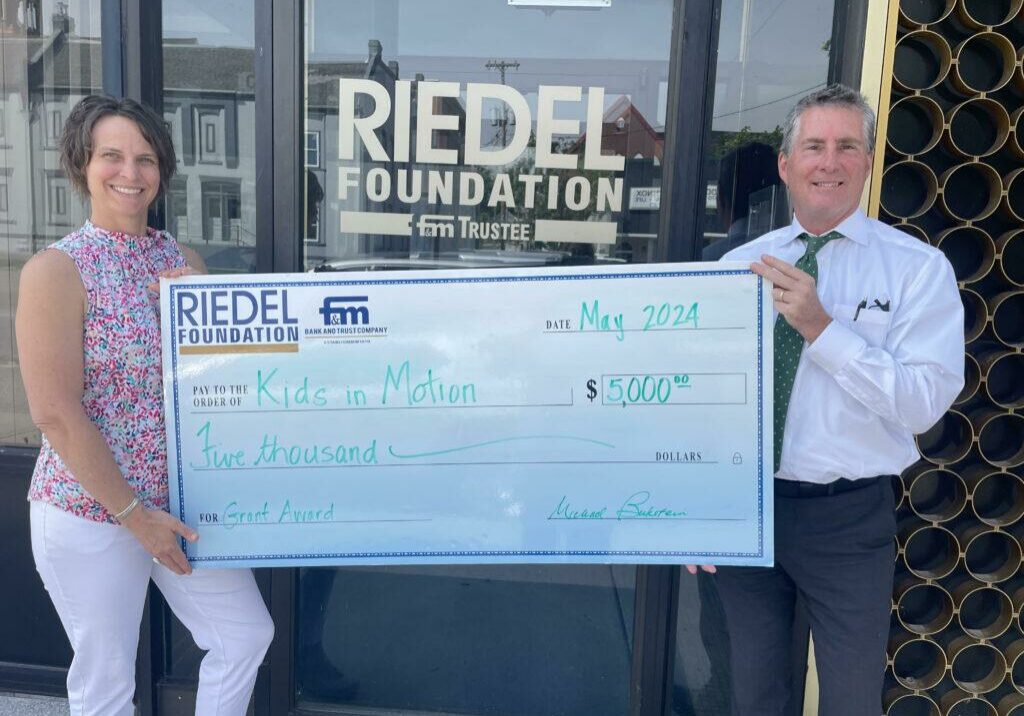 Kids in Motion Coordinator Emily Trevathan accepts a $5,000 grant award from Riedel Trustee Paul Richards.