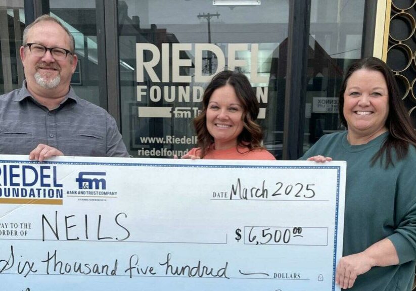 Caption:  Riedel Trustee Michael Gaines presents a $6,500 grant award to and Independent Living Director Morgan Evans and NEILS Executive Director Brooke Kendrick.