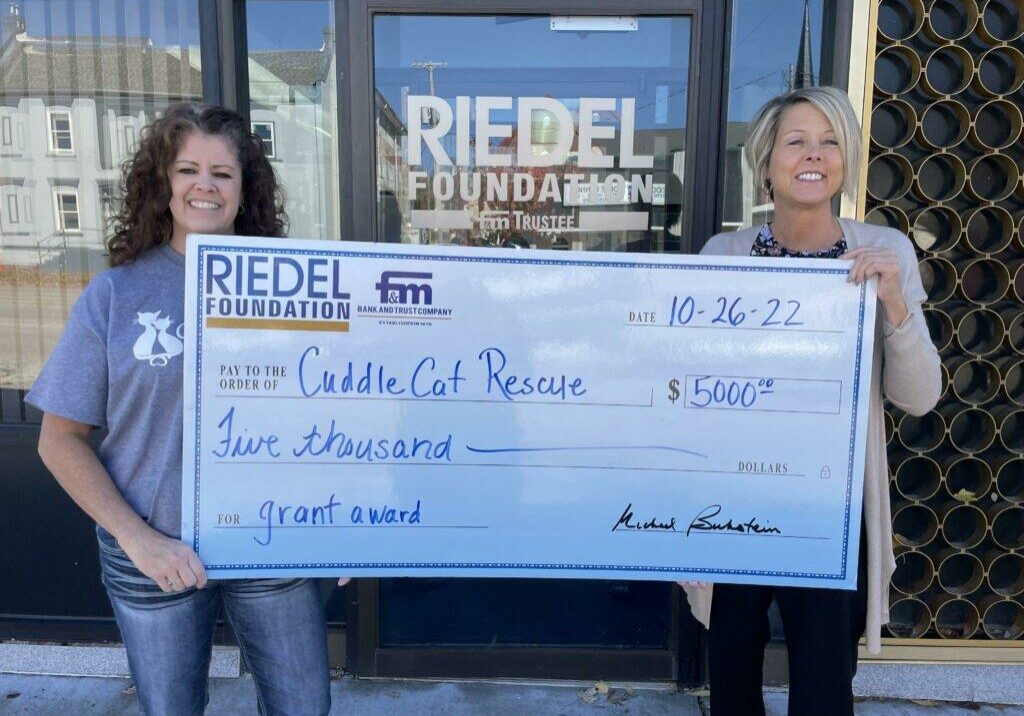 Riedel Trustee April Baldwin presents a check to Maria Poindexter with Cuddle Cat Rescue